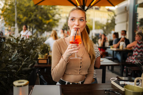 Young woman enjoying Aperol Spritz at outdoor cafe in Vienna