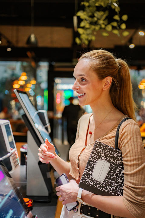 Woman smiling while making contactless payment in shop