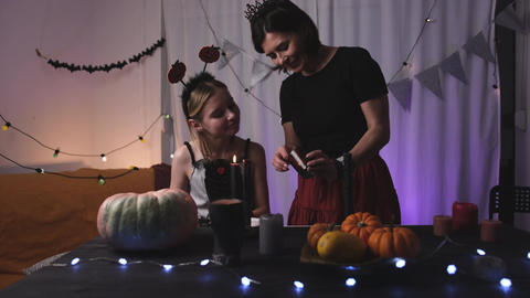 Mother Helping For Daughter To Light Up A Halloween Candles