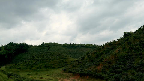 Lush green hills under a dramatic cloudy sky creating a serene and picturesque landscape scene