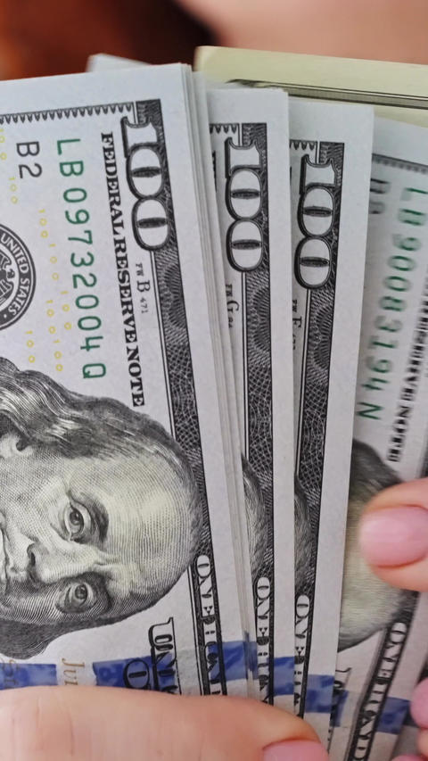 Hand holding hundred dollar bill stack cash close up money finance wealth