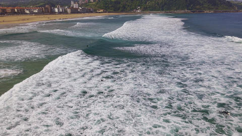 Surfers riding waves near sandy beach coastline