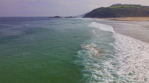 Surfers riding waves near sandy beach coastline