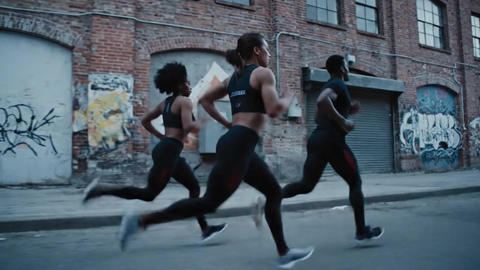 Diverse group of friends jogging on a city street in a continuous tracking shot