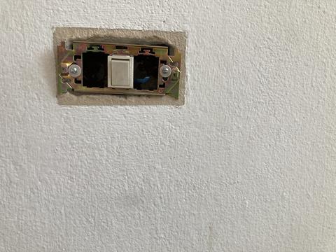 incomplete light switch installation on a white plaster wall