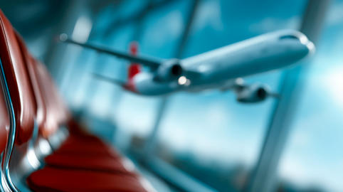 Airplanes viewed through an airport terminal window at sunset, with empty passenger seats and blurre