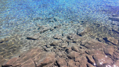 Sunlight Reflecting on Clear Rocky Water of Mountain Lake