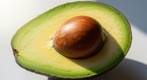 Close up of ripe avocado with sparkling water droplets, resting on clean white background