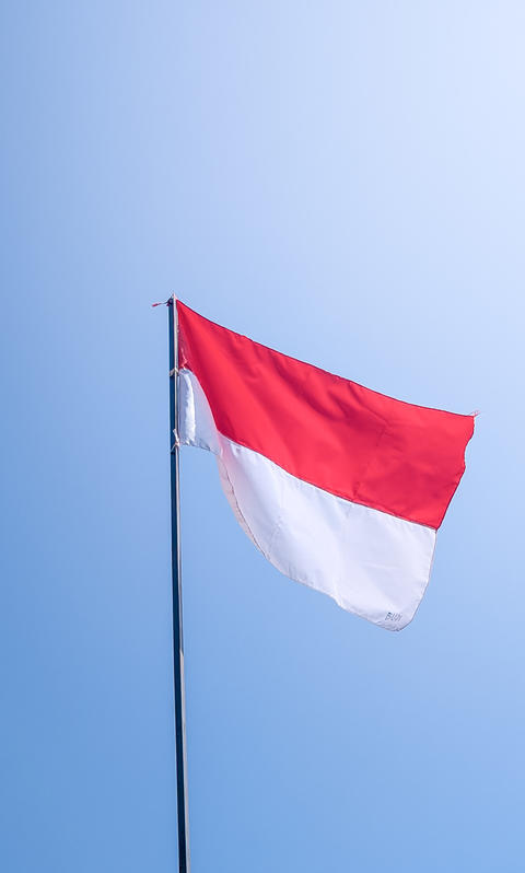 Indonesian Flag Waving on Flagpole Against Blue Sky for Independence Day and National Celebration