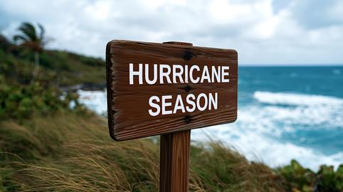 Wooden sign displaying hurricane season warning near ocean