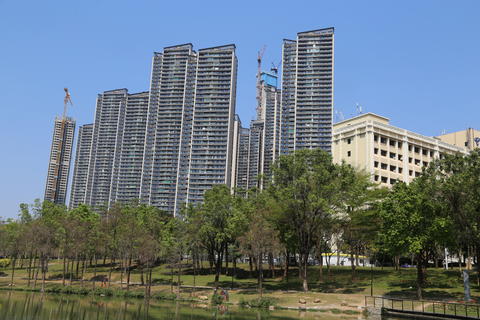 A group of high-rise residential buildings under construction stand tall against the blue sky, with 
