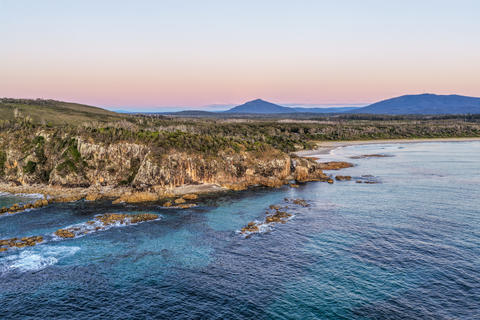 Aerial view of the rugged rocky headland at Diamond Head surrounded by clear turquoise ocean water