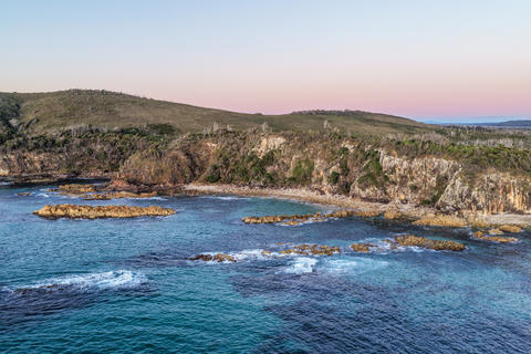 Aerial view of the rugged rocky headland at Diamond Head surrounded by clear turquoise ocean water