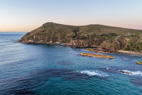 Aerial view of the rugged rocky headland at Diamond Head surrounded by clear turquoise ocean water