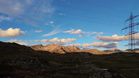 Mountain landscape with power lines reflecting in small lake at sunset