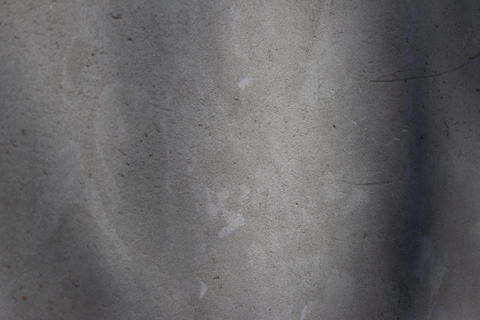 Rough concrete wall featuring a detailed textured surface with uneven grey tones