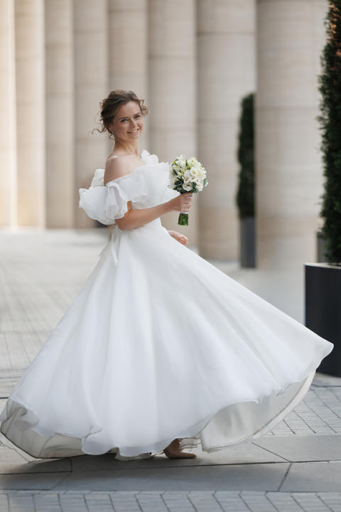 Bride twirls in a full white gown among stone columns