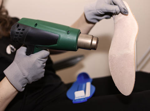 Podiatrist shaping custom orthopedic insole during foot treatment