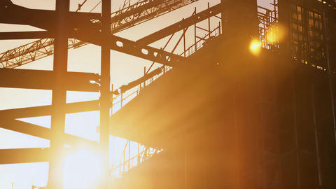 Silhouette of Construction Scaffolding and Steel Beams Against Sunrise or Sunset
