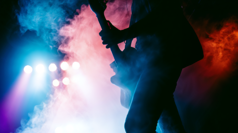 Silhouette of a Guitarist Performing on Stage with Smoke and Stage Lights