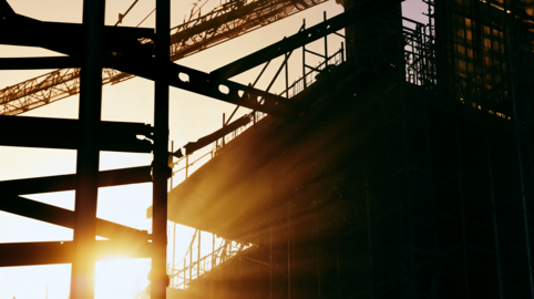 Silhouette of Construction Scaffolding and Steel Beams Against Sunrise or Sunset