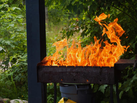 burning wood with a bright orange flame inside a metal grill