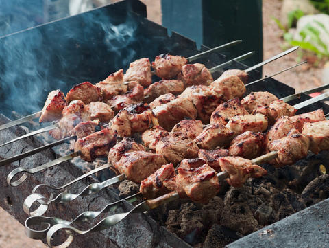 Crispy traditional pork shashlik grilled on skewers over coals