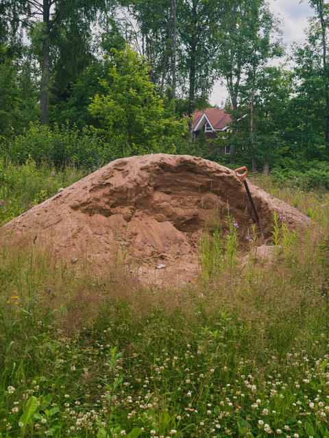 large pile of construction or backfill sand with a shovel stuck into it