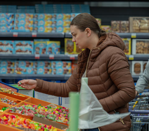 Girl choosing candy. Shopper excitedly chooses bright candies amid sale and
