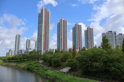 Modern high rise residential apartment buildings along green waterfront park under blue sky