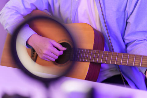 Cropped shot of person playing acoustic guitar during music studio session