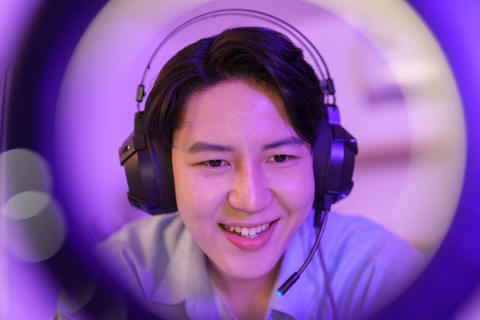 Asian young man wearing gaming headset with microphone streaming online