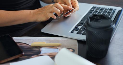 Hands holding credit card over laptop during online shopping on desk with coffee