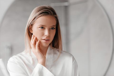 Young Woman Applying Skincare Routine In Bathroom, Focused And Calm, Beauty