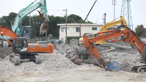 Multiple pieces of heavy machinery operating at a demolition site [Vertical video]