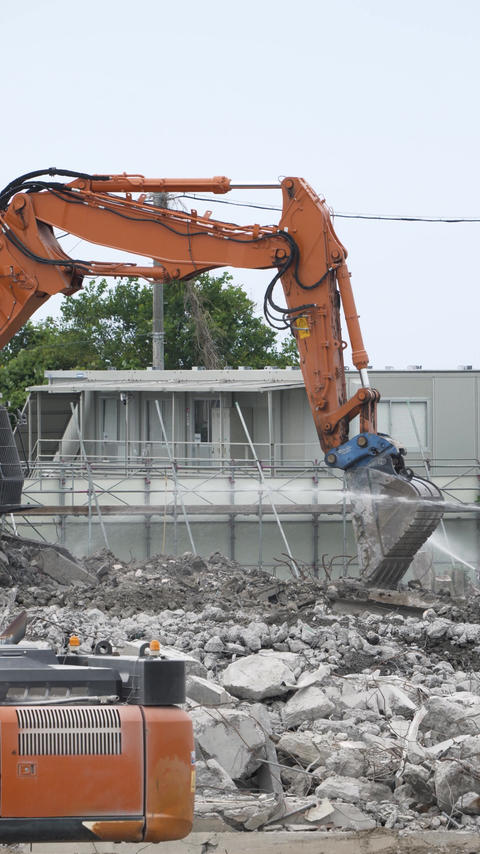 Multiple pieces of heavy machinery operating at a demolition site [Vertical video]