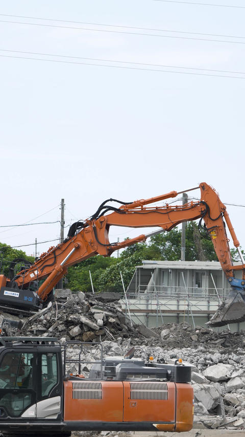 Multiple pieces of heavy machinery operating at a demolition site [Vertical video]