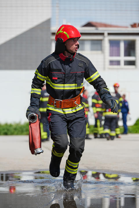 Firefighter Running With Hose During Emergency Training Drill In Protective Gear