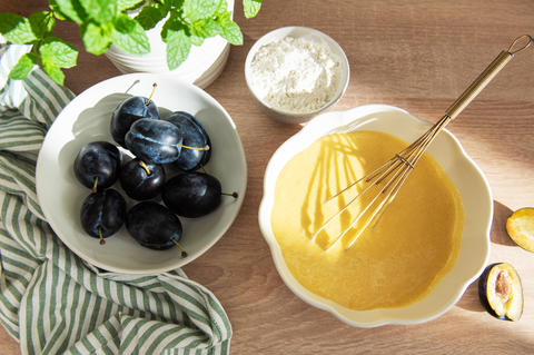 Baking plum cake ingredients with batter and flour