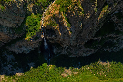 Aerial view of tall waterfall cascading down rocky mountain face