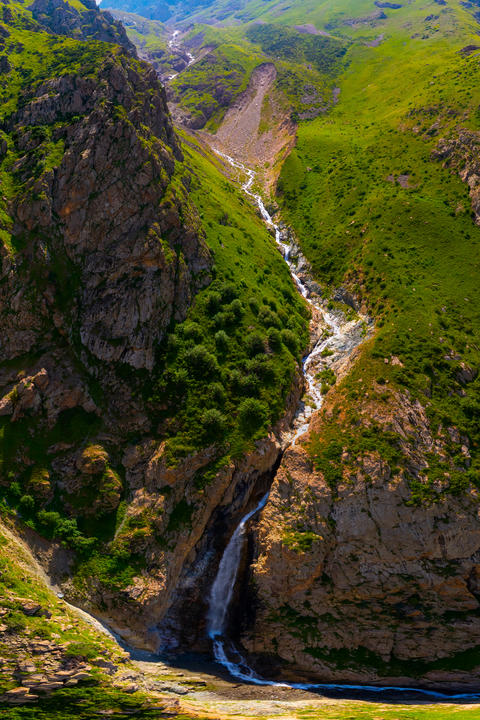 Aerial view of mountain valley with waterfall and rocky cliffs