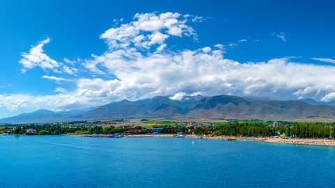 Vibrant beach scene at blue Issyk-Kul lake with parasailer