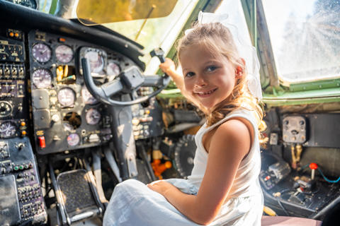 Young girl exploring airplane cockpit and holding flight controls. First