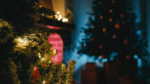 Fireplace lit near Christmas tree in dark room at night copy space