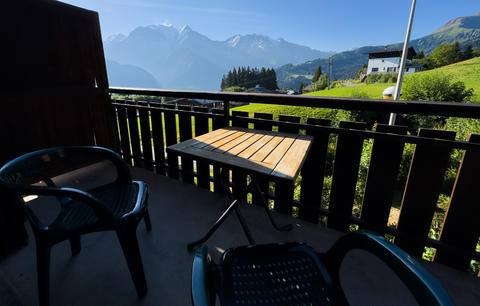 cozy wooden balcony with comfortable lounge chair overlooking scenic green