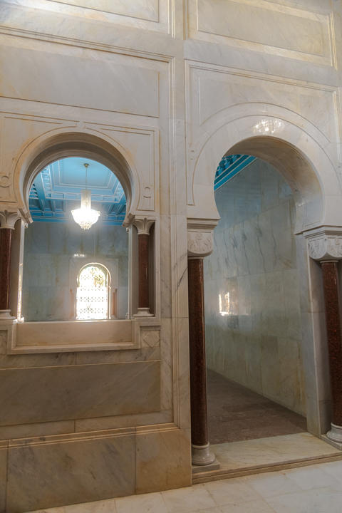 Interior view through ornate arch into room with turquoise ceiling and hanging lamp, with arch