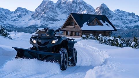 Atv with snowplow clearing snow path at mountain cabin