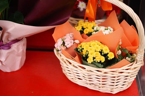 A vibrant assortment of flowers arranged in a basket sits atop a striking red