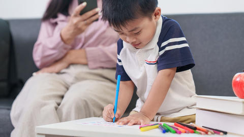 Asian boy drawing with markers at home for early childhood education