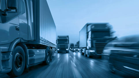 A convoy of trucks is moving along a multi‑lane highway with a dynamic blur effect